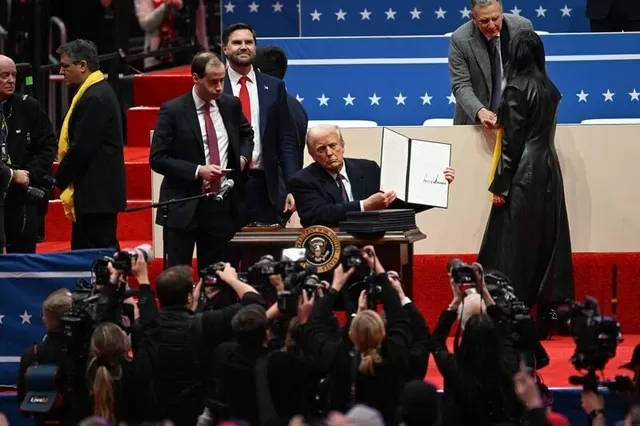 Tổng thống Donald Trump cầm một sắc lệnh hành pháp đã ký tại Capital One Arena ở Washington DC vào ngày 20/1/2025. Ảnh: Bloomberg