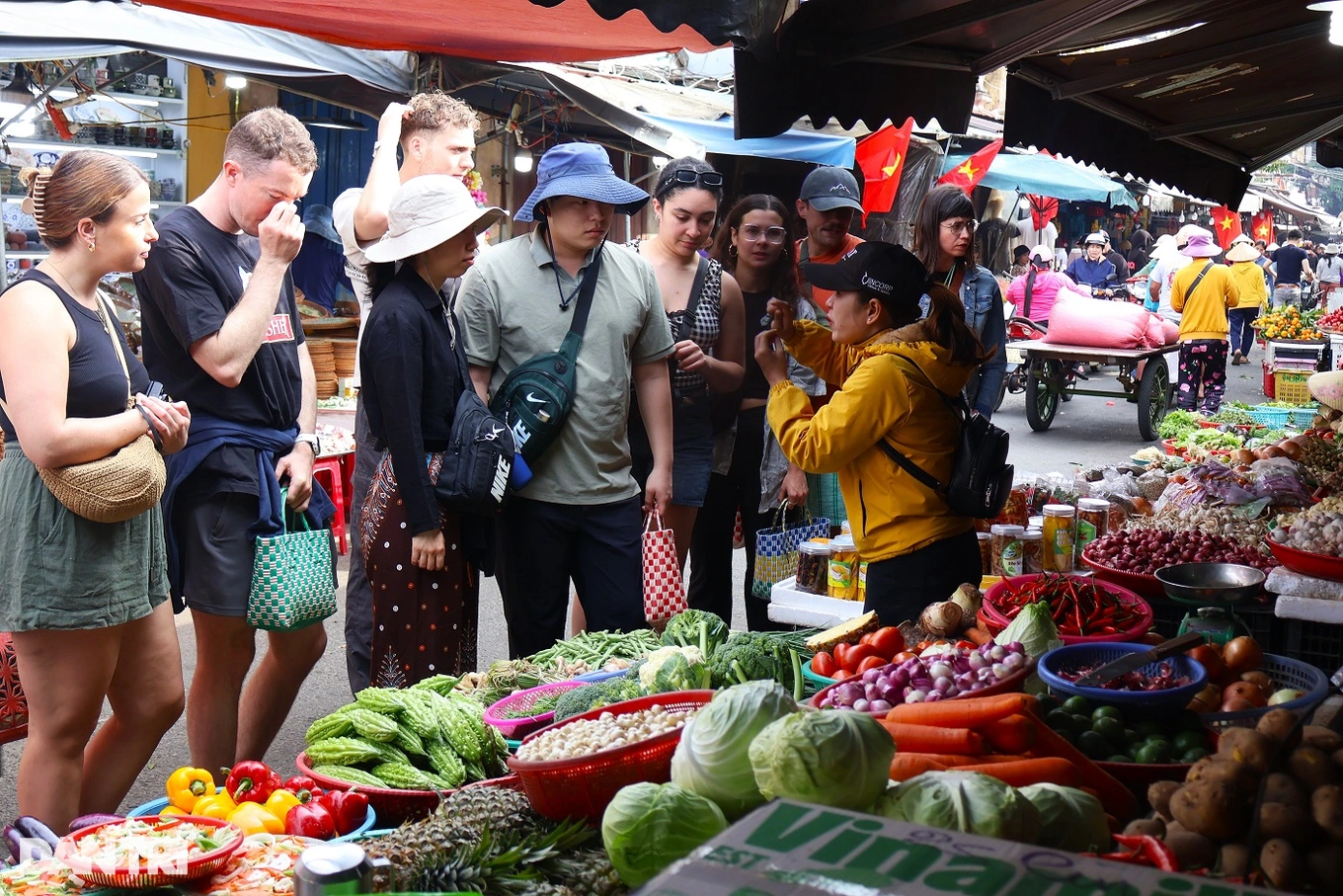 นักท่องเที่ยวชาวตะวันตกเพลิดเพลินกับการเดินเล่นรอบตลาดเต๊ตในวันสุดท้ายของปีในเมืองโบราณฮอยอัน