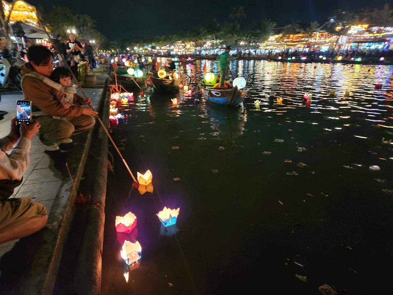 Un père et son fils lâchent des lanternes de fleurs sur la rivière Hoai, souhaitant de bonnes choses et du bonheur pour la nouvelle année. Photo : Q.T