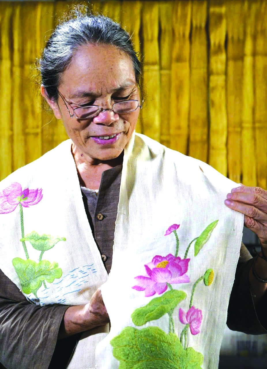 Meritorious artisan Phan Thi Thuan introduces a silk scarf made from lotus silk. Photo: Tuyet Linh.