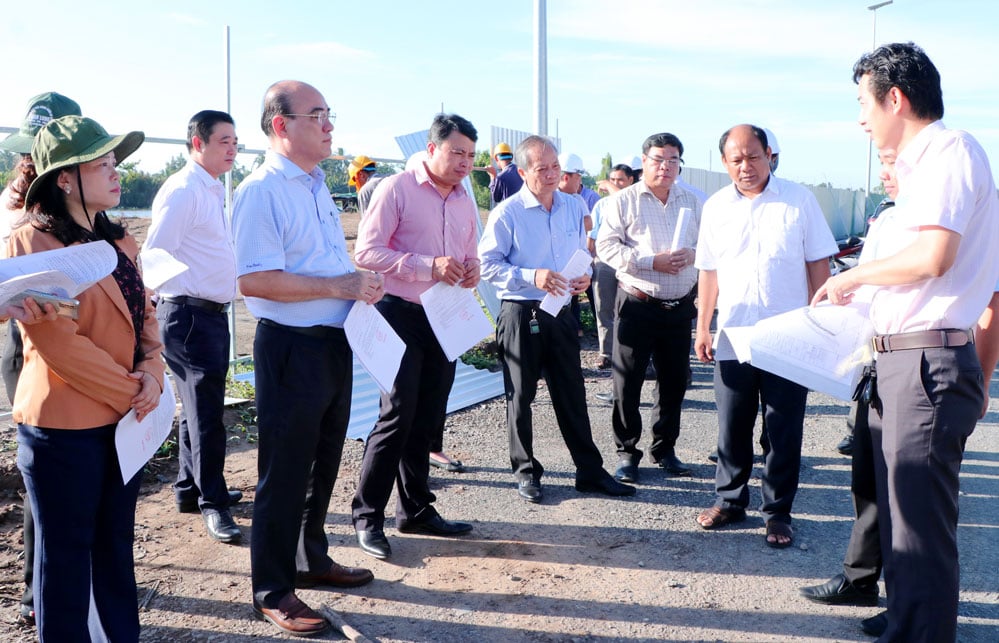 Genosse Nguyen Van Tuan (dritter von links) und die Arbeitsdelegation hörten sich einen Fortschrittsbericht über das Projekt zur Verhinderung von Erdrutschen am Lang-Flussufer in Verbindung mit der Tribüne für Ngo-Bootsrennen an.