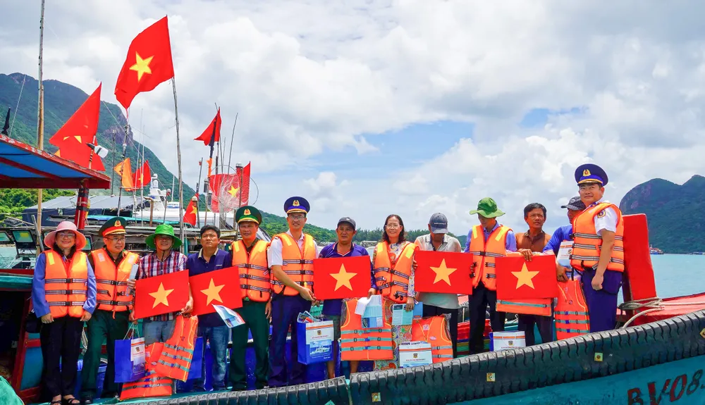 Cán bộ, chiến sĩ Bộ Tư lệnh Vùng Cảnh sát biển 3 cùng đoàn công tác trao tặng cờ Tổ quốc, nhu yếu phẩm cho ngư dân Côn Đảo.jpg