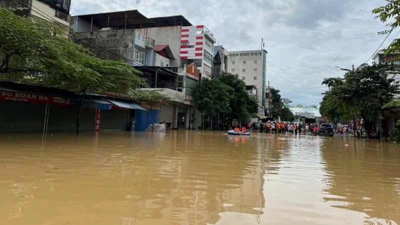 ទឹកជំនន់​នៅ​តំបន់​ផ្លូវ​ប្រសព្វ​សង្កាត់ Phan Dinh Phung ។ ពីចម្ងាយ អាជ្ញាធរ និងប្រជាពលរដ្ឋបានប្រមូលផ្តុំគ្នាជួយទូកដឹកប្រជាពលរដ្ឋចេញពីតំបន់លិចលង់។ (រូបថត៖ TUAN SON)។
