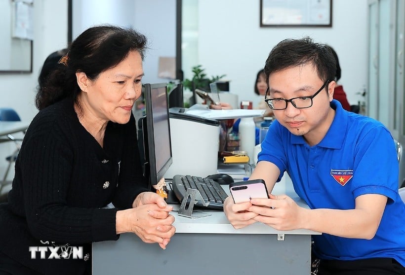 Mitglieder der Jugendunion des Bezirks Hang Bo (Hoan Kiem, Hanoi) unterstützen Menschen bei der Erledigung öffentlicher Verwaltungsvorgänge per Smartphone. (Foto: Pham Hau/VNA)