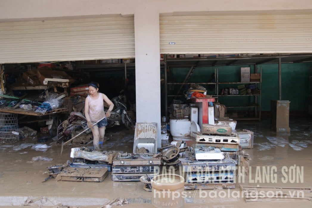 תושבי קומונת ין בין מנקים בוץ לאחר שהשיטפון שכך.