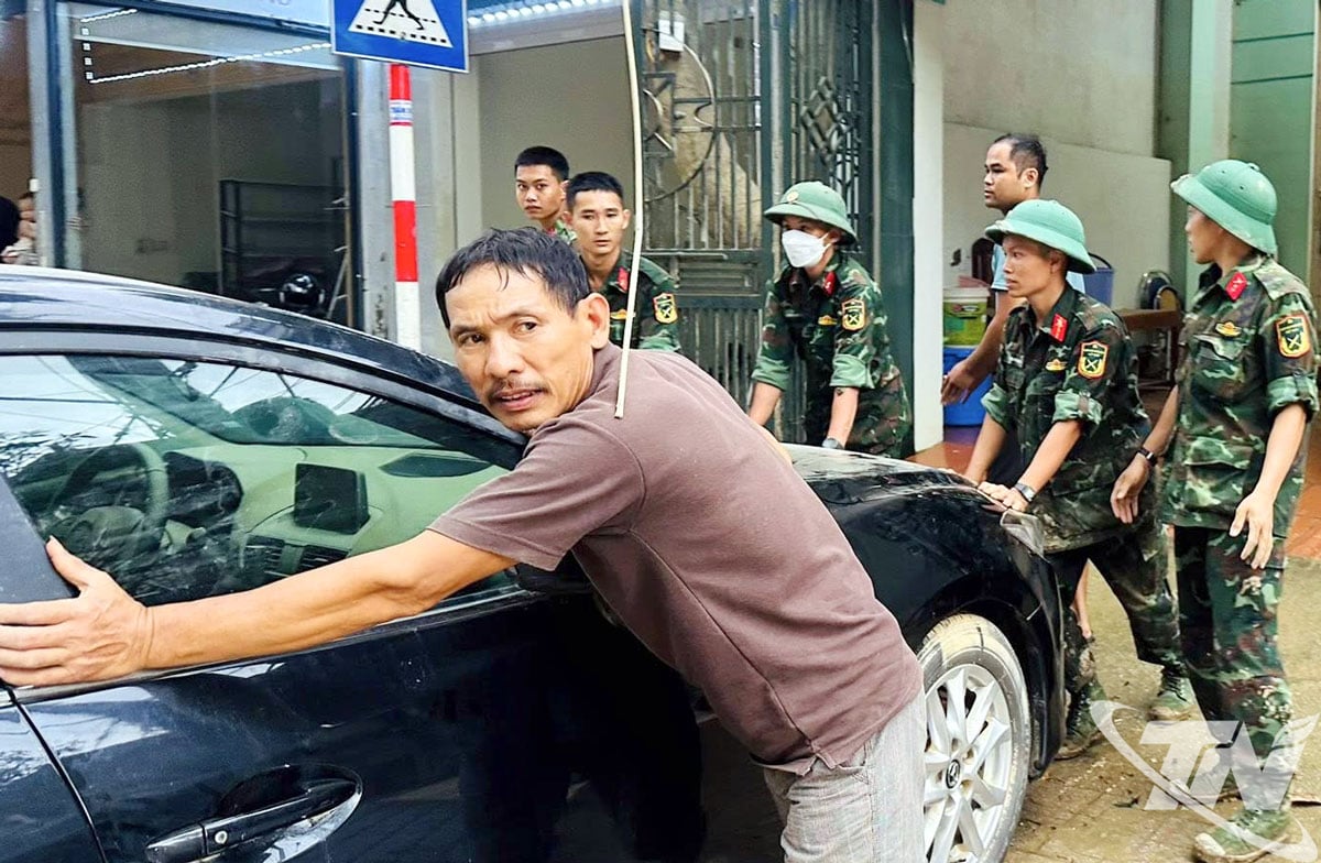 Para perwira, tentara, dan warga kecamatan Phan Dinh Phung saling membantu membersihkan rumah dan membawa mobil untuk diperbaiki setelah banjir.
