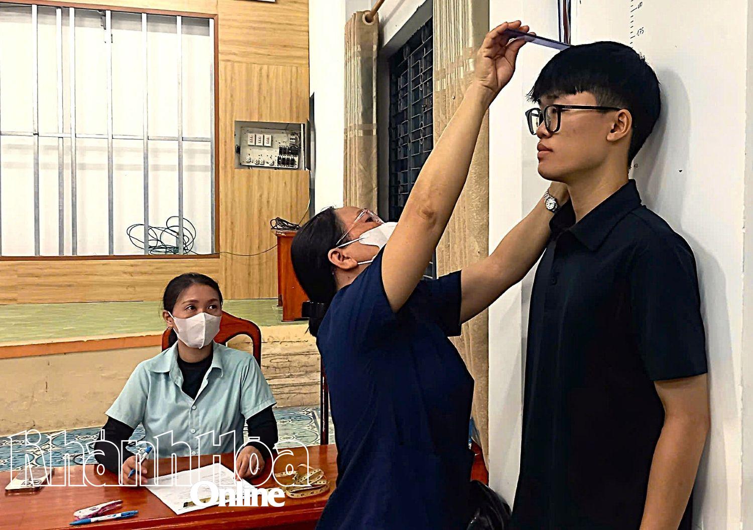 Nhân viên y tế đo chiều cao cho thanh niên.