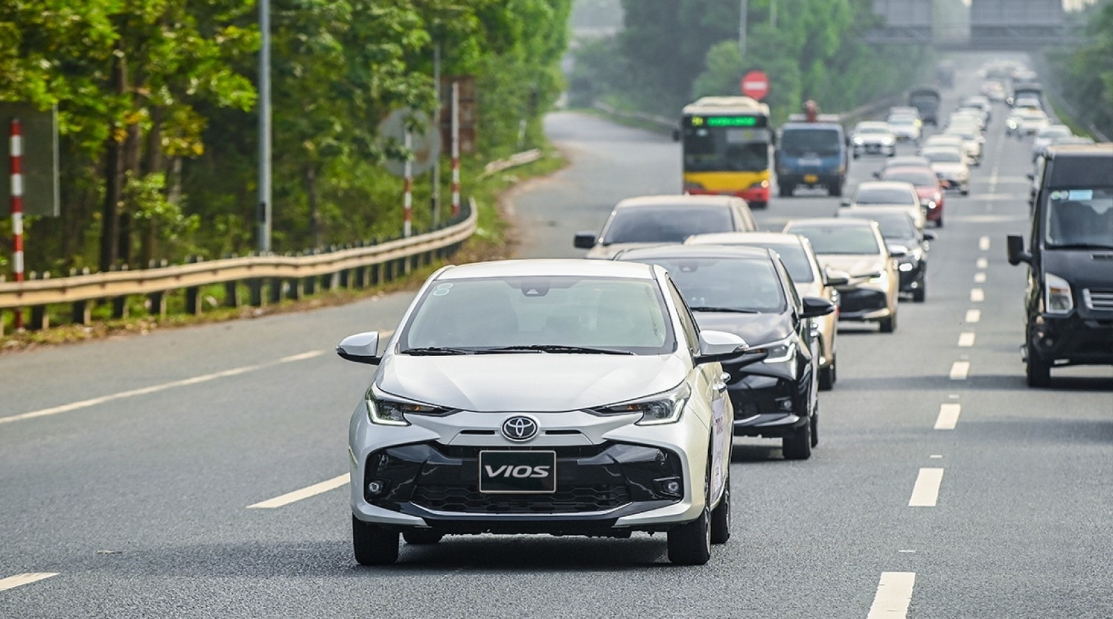 Gambar Toyota Vios putih melaju di jalan yang ramai.