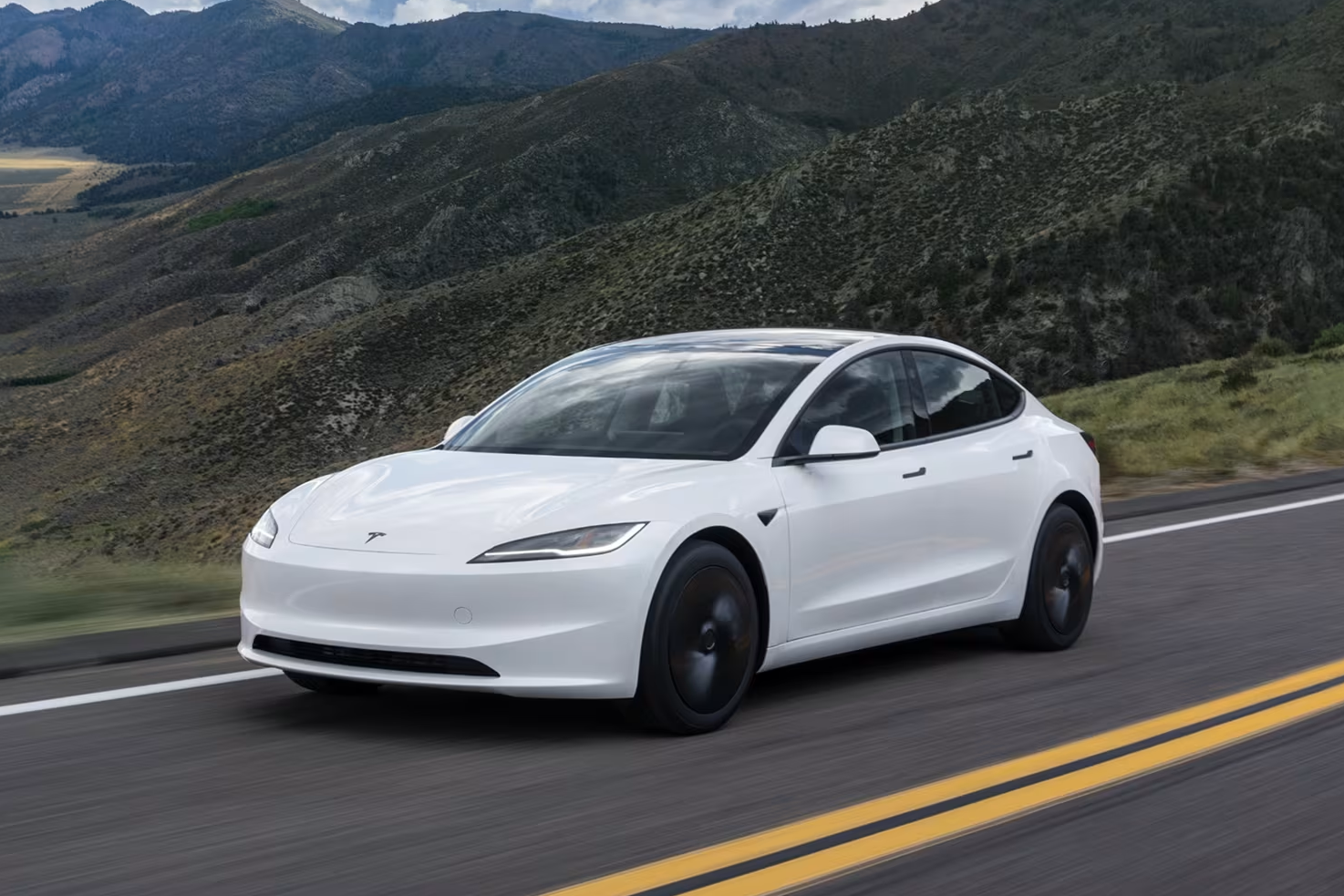 Utsiden av en hvit Tesla Model 3 elbil som beveger seg på veien.