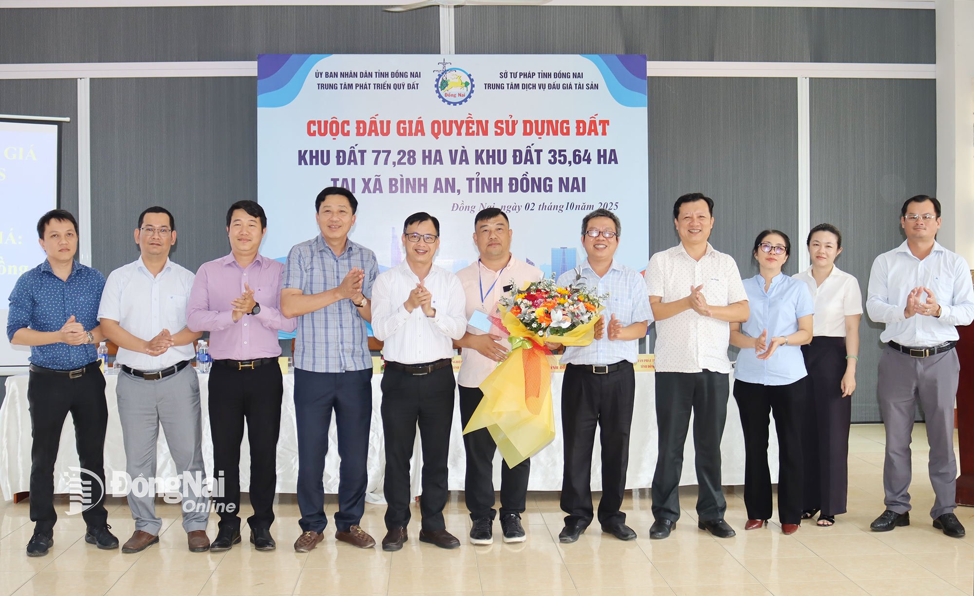 Đại diện lãnh đạo Trung tâm Phát triển quỹ đất tỉnh Đồng Nai và các sở, ban, ngành tặng hoa chúc mừng khách hàng trúng đấu giá khu đất hơn 35ha. Ảnh: Hoàng Lộc

