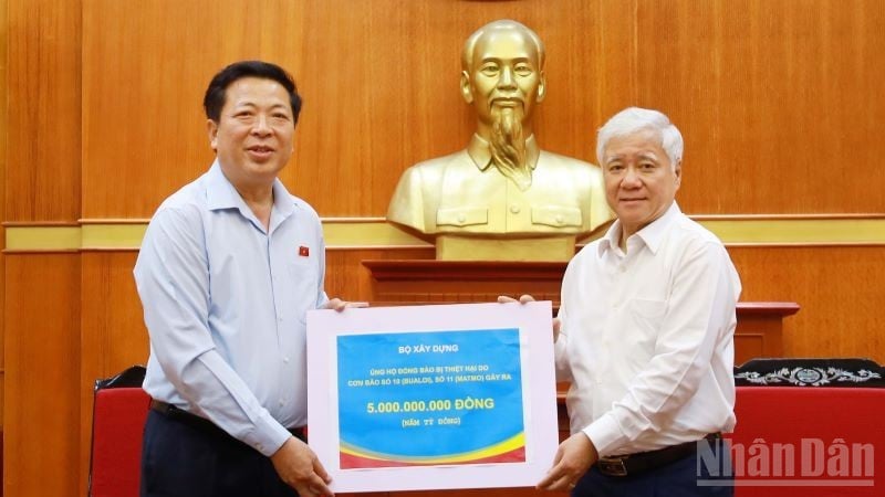 Byggminister Tran Hong Minh (vänster) överlämnade 5 miljarder VND för att stödja översvämningsoffren genom Vietnams fosterlandsfronts centralkommitté.