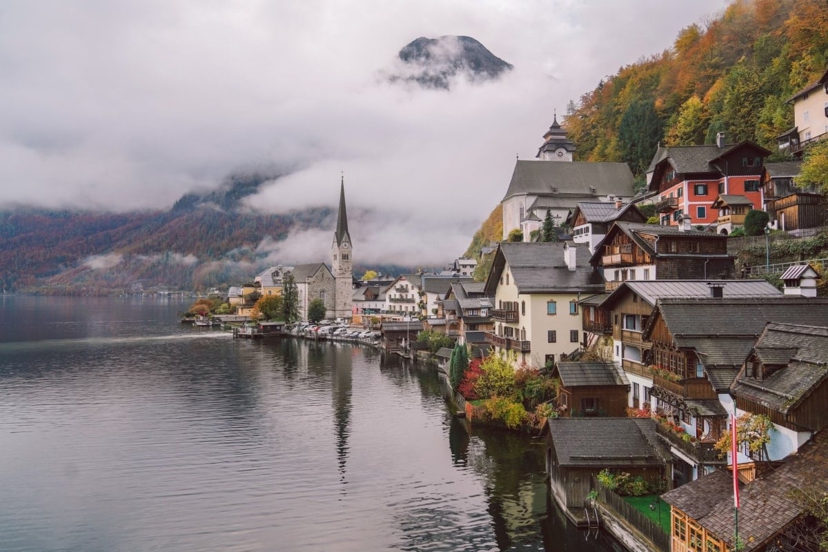 Panoramautsikt över staden Hallstatt speglas i den klarblå sjön Hallstätter på en vacker höstdag.