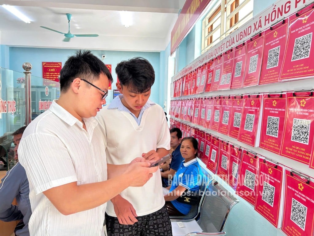 Les spécialistes du Centre de services d'administration publique de la commune de Hong Phong guident les gens dans la réalisation de procédures administratives en ligne sur des smartphones.