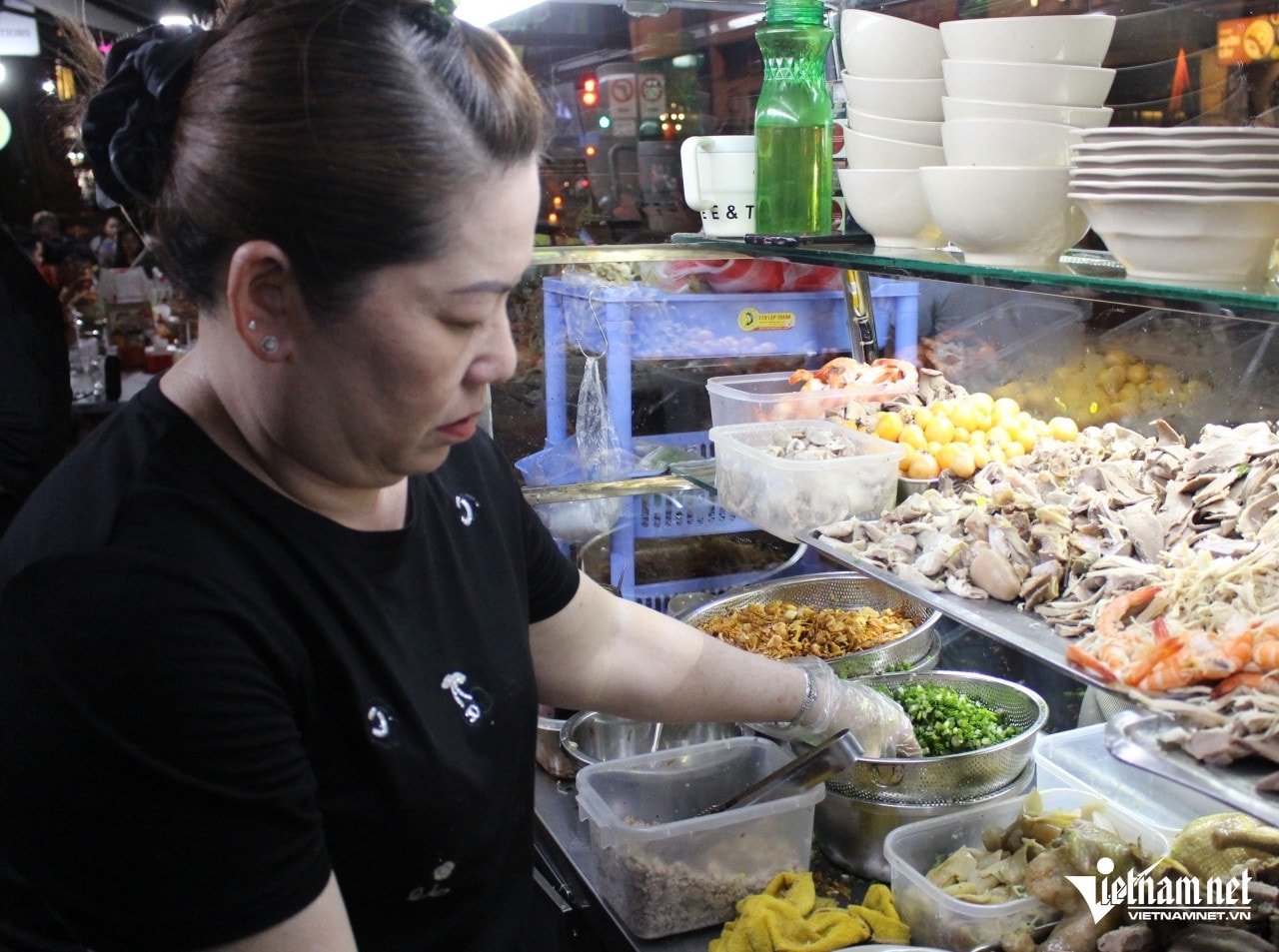 Ms. Trang, the owner of the noodle shop, is preparing food for customers.