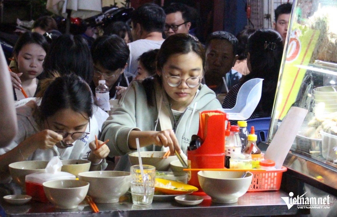 Two young people Thu Ngan and My are enjoying noodles after waiting.
