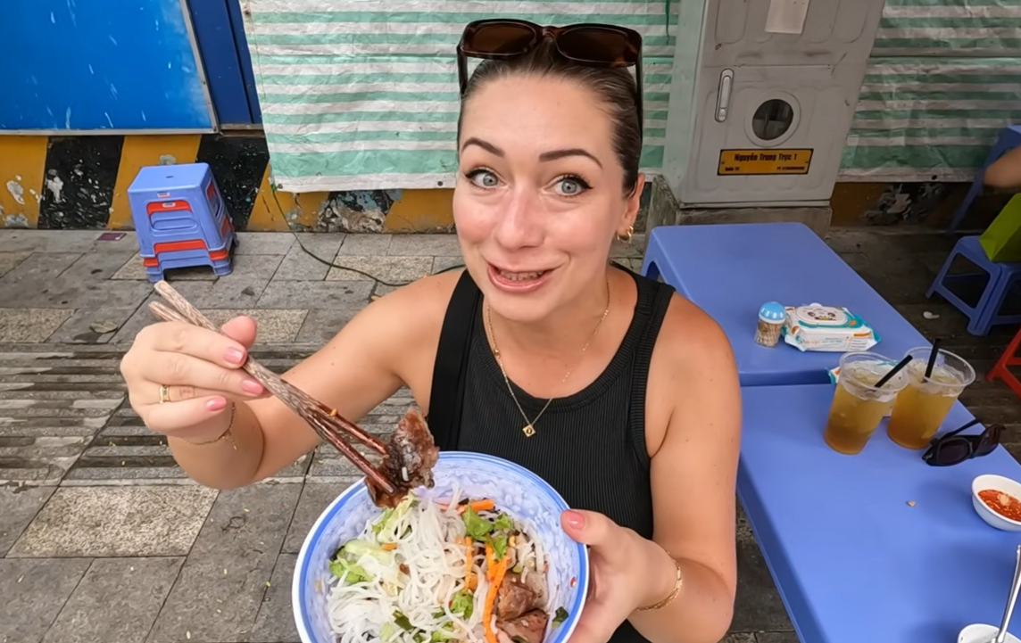 Hai du khách Anh thưởng thức bún thịt nướng tại một quán vỉa hè ở TPHCM.