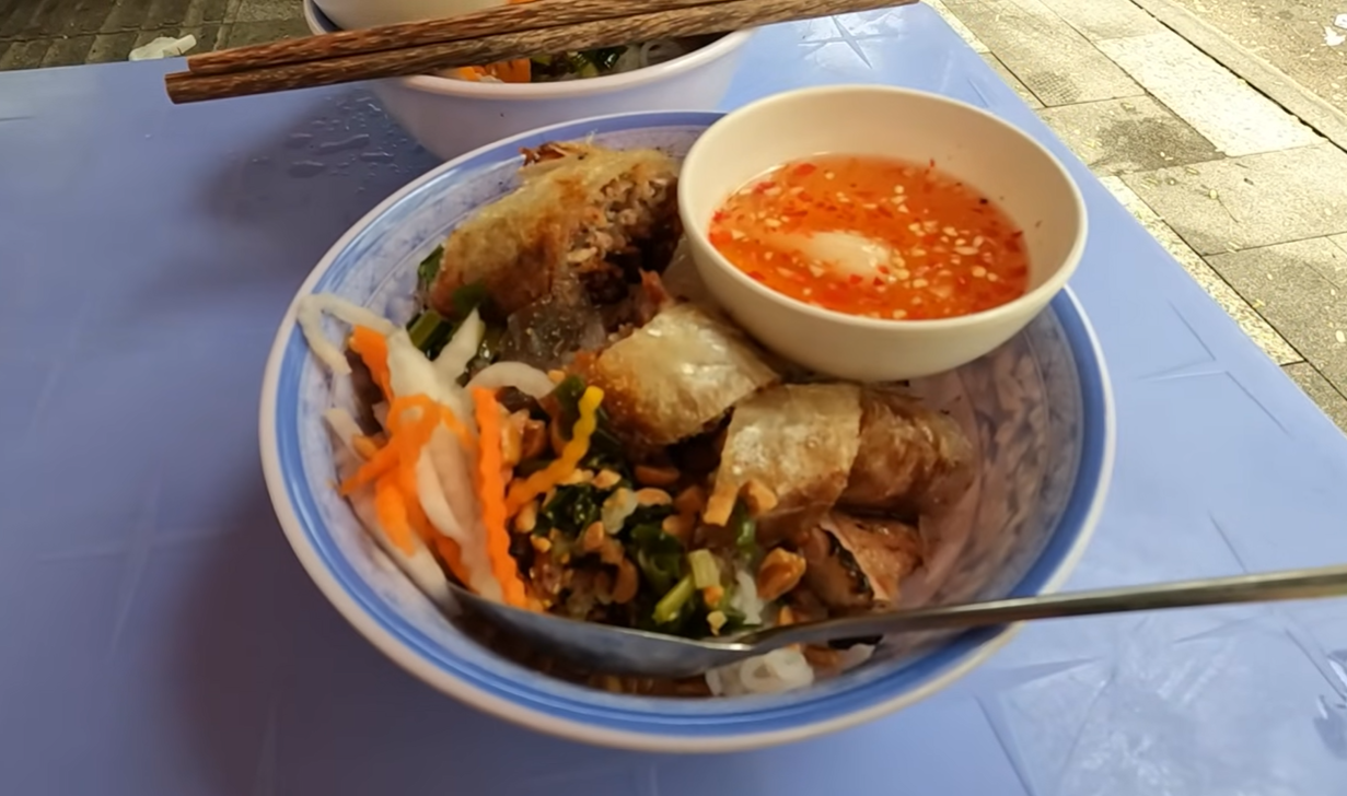 Một suất bún thịt nướng chả giò đầy đủ với các loại rau ăn kèm.