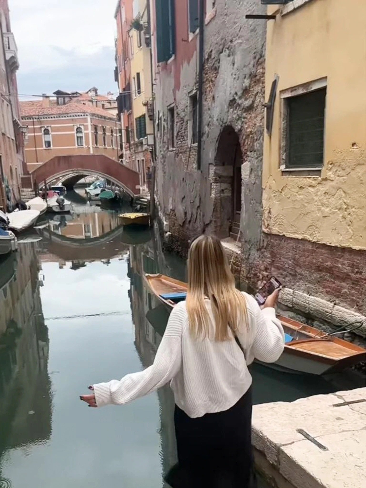 Turister sitter på trapper ved siden av en kanal i Venezia.