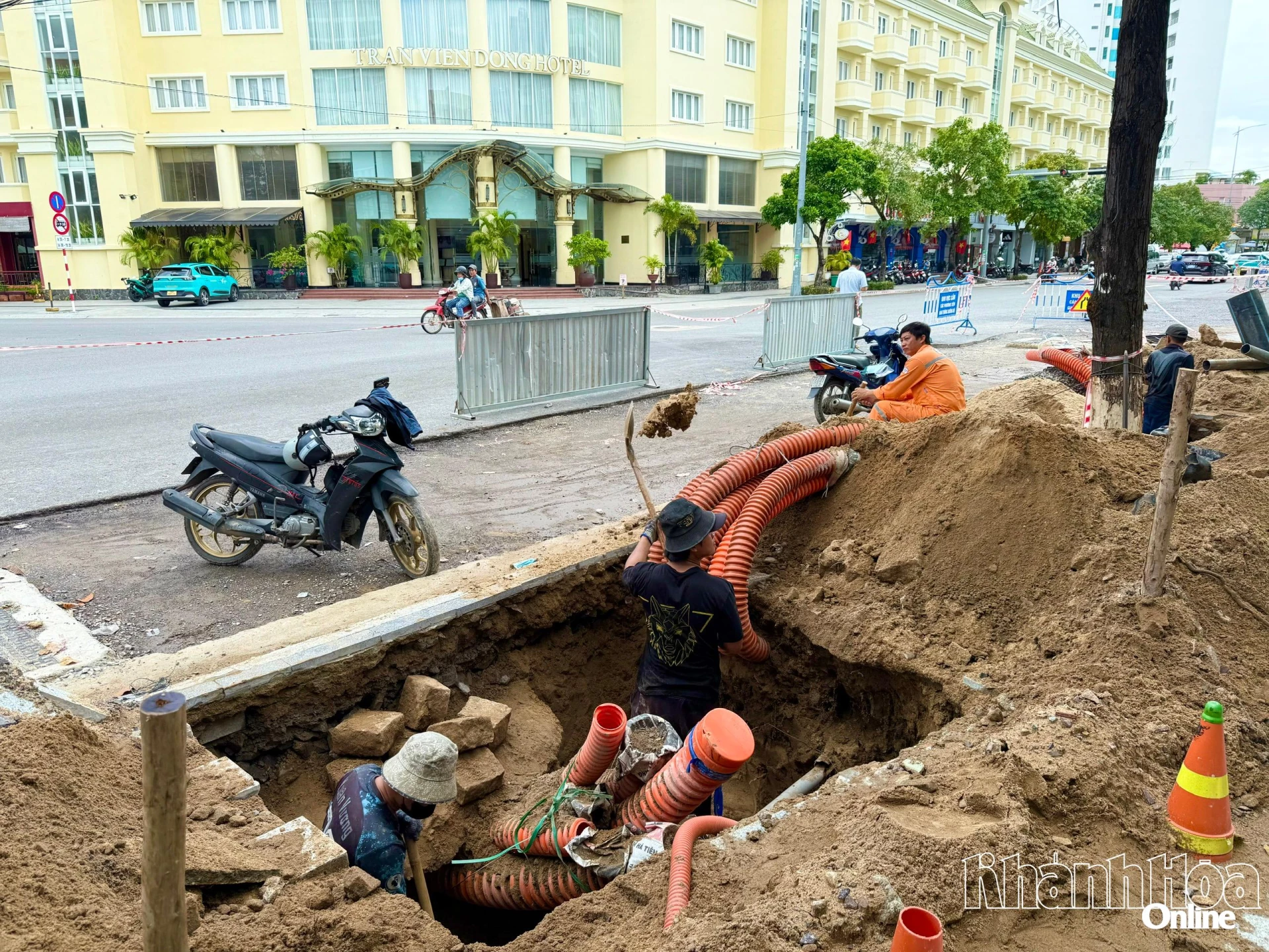 Trabalhadores estão cavando infraestrutura técnica subterrânea na calçada da Rua Le Thanh Ton.