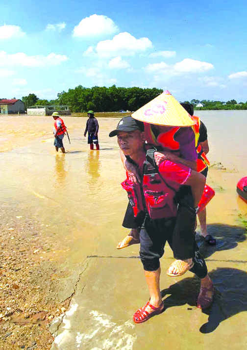 Herr Mau Tuan bär en äldre person i Thai Nguyen-provinsen från ett djupt översvämmat område till en säker plats - Foto: NVCC