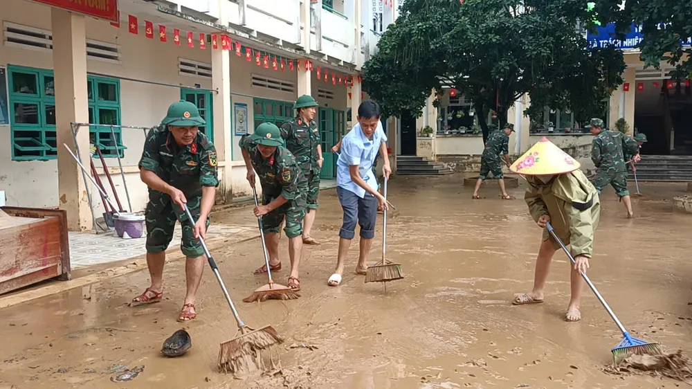 Städa upp leran som blev kvar efter översvämningen på en skola