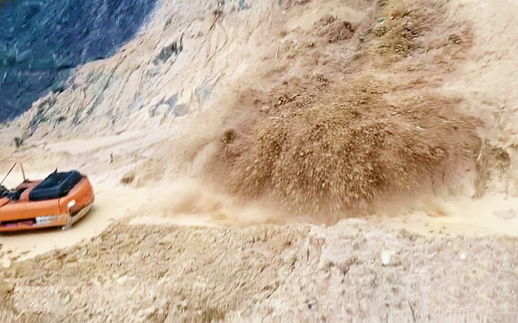 Xe múc đang xúc dọn đất thì ngọn đồi sạt lở đổ ầm xuống - Ảnh 1.