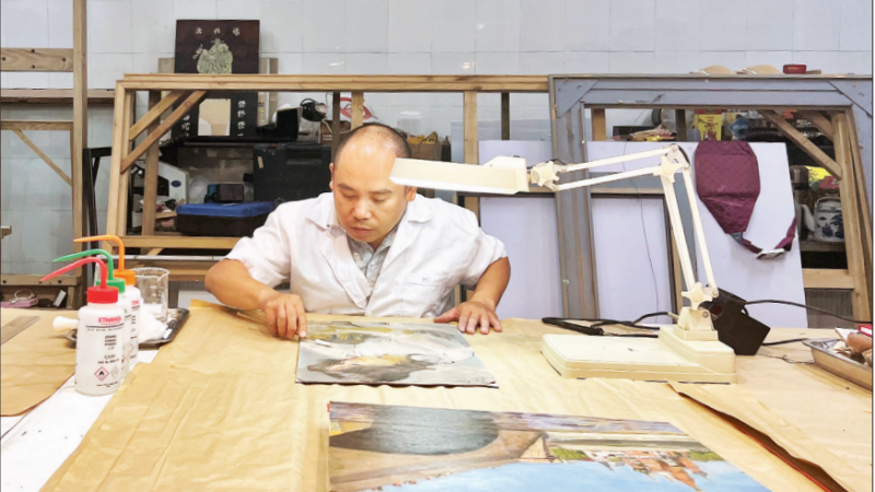 El señor Nguyen Manh Hai limpió el cuadro del famoso pintor Tran Van Can.