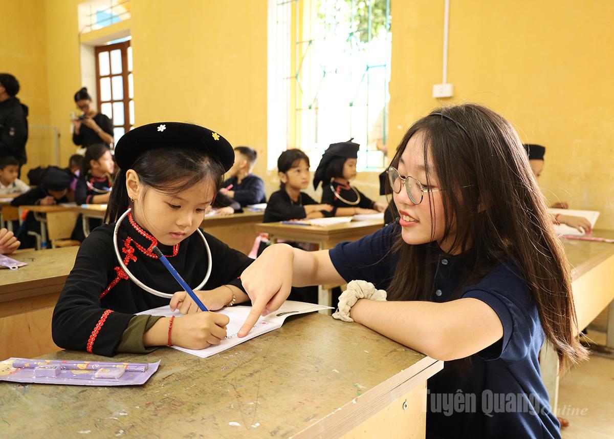 Voluntarii Clubului Tay Roots îi îndrumă cu entuziasm pe elevi în scris și în familiarizarea lor cu propoziții de bază în limba engleză.