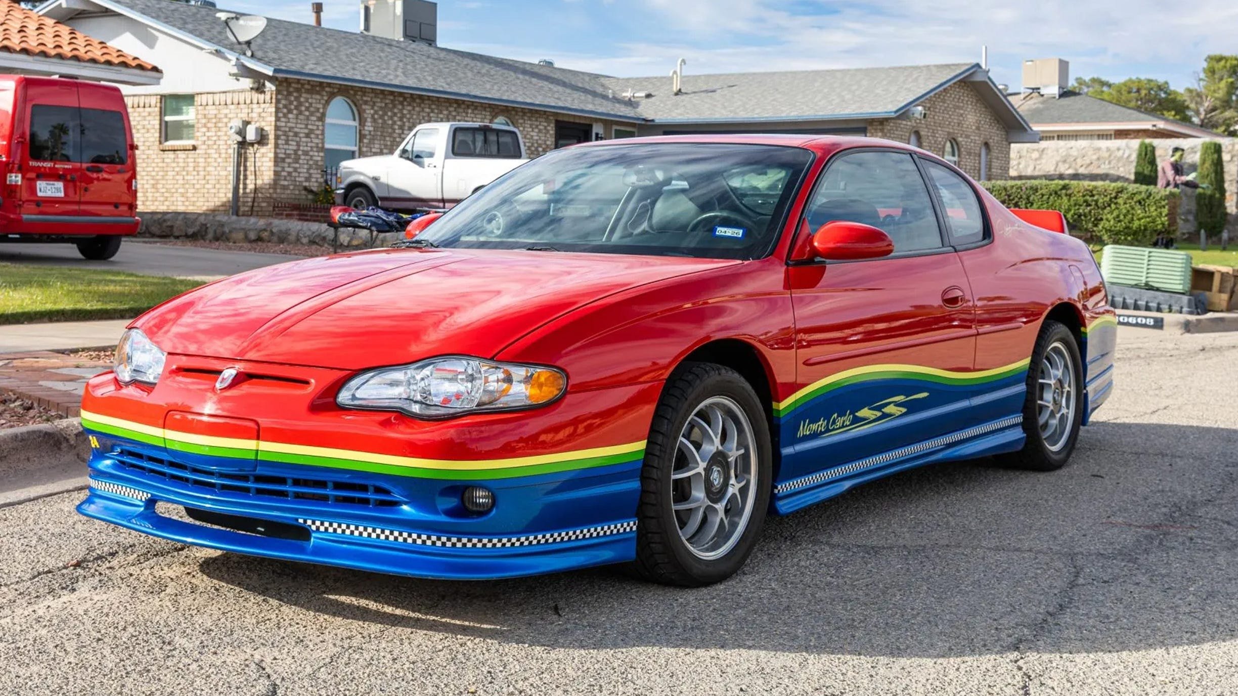 Röd coupé framifrån, 3/4-vy, motorhuvsventilation, flerfärgade ränder, näthjul.