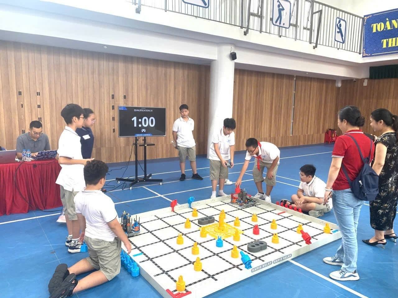 Además de los estudios, la escuela ha organizado numerosas actividades creativas y espacios tecnológicos a gran escala en el aula de ciencias, tecnología, ingeniería y matemáticas (STEM). Entre ellos destaca el Torneo de Robótica Cau Giay VEX IQ 2025, que se celebró por primera vez en la escuela a finales de septiembre. Foto: Petrovietnam. Không chỉ dừng lại ở học tập, từ phòng STEM, nhà trường đã tổ chức nhiều hoạt động sáng tạo và các sân chơi công nghệ quy mô, nổi bật nhất là Giải đấu Robotics Cầu Giấy VEX IQ 2025 - lần đầu tiên được tổ chức tại trường vào cuối tháng 9 vừa qua. Ảnh: Petrovietnam.