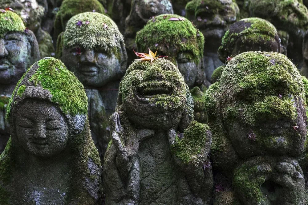 Moss-covered stone statues with various expressions at Otagi Nenbutsu-Ji Temple.