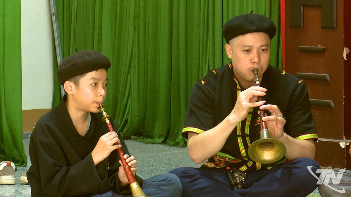 Trieu Tan Phat (stânga), o persoană Dao din satul Mo Sat, exersează cântatul la flaut Pi Le cu adulții din sat.