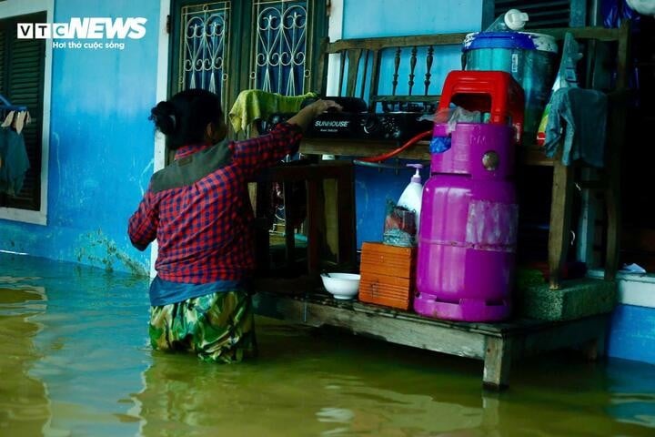 মানুষ বন্যার পানিতে ভিজে, তাদের পরিবারের জন্য খাবার রান্না করে।