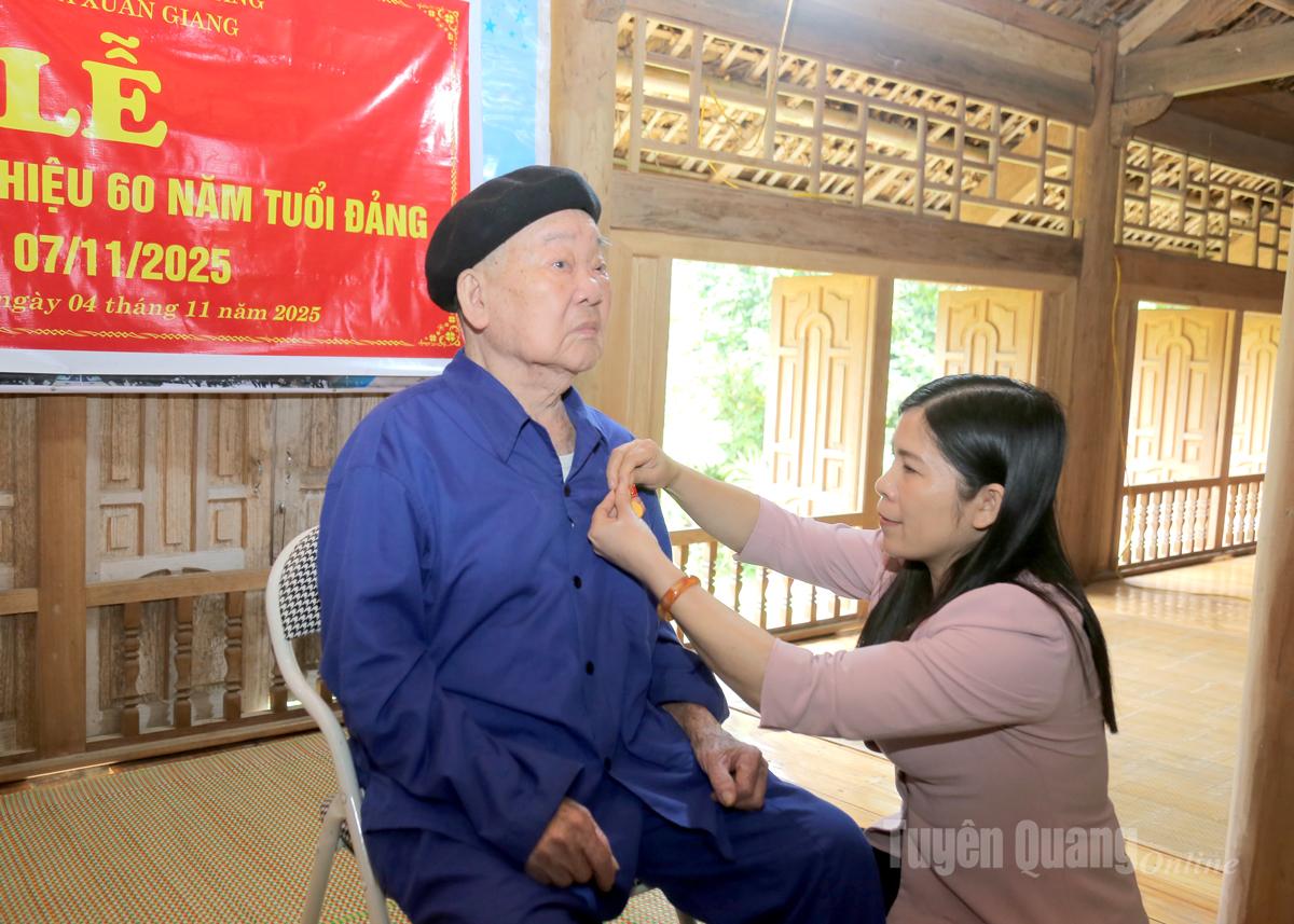 Nestleder i det provinsielle folkerådet Le Thi Thanh Tra festet 60-årsmedlemsmerket for partiet på partimedlemmet Hoang Quang Khai.