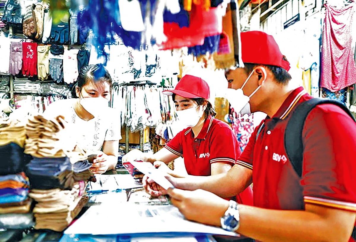 বাণিজ্যিক ব্যাংকগুলি ডিজিটাল পেমেন্ট অ্যাপ্লিকেশন ব্যবহারে ক্ষুদ্র ব্যবসায়ী এবং ব্যবসায়িক পরিবারগুলিকে সহায়তা করার জন্য সক্রিয়ভাবে সরাসরি বাজারের স্টলে কর্মী পাঠায়। NHTM chủ động cử nhân viên đến trực tiếp các sạp chợ hỗ trợ tiểu thương, hộ kinh doanh sử dụng các ứng dụng thanh toán số