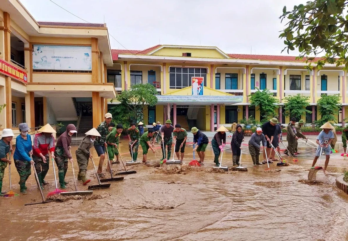 Le Thuy Commune Police and teachers cleaned up mud and dirt to promptly put schools back into normal operation - Photo: N.H