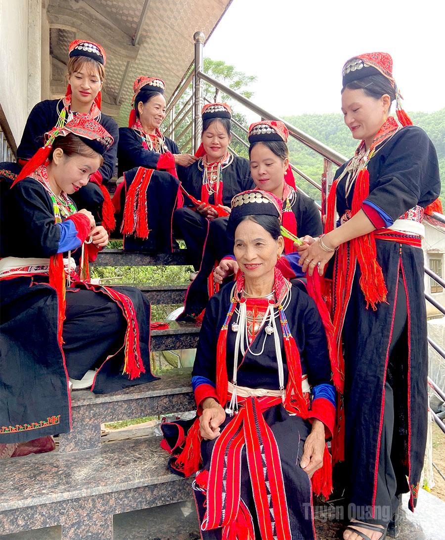 Kostum wanita Dao menampilkan warna merah yang menarik pada latar belakang hitam.