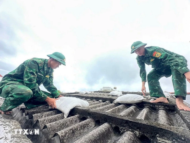 Soldater hjelper folk med å legge sandsekker på takene sine for å hindre at de blåses av under uvær. (Foto: VNA)