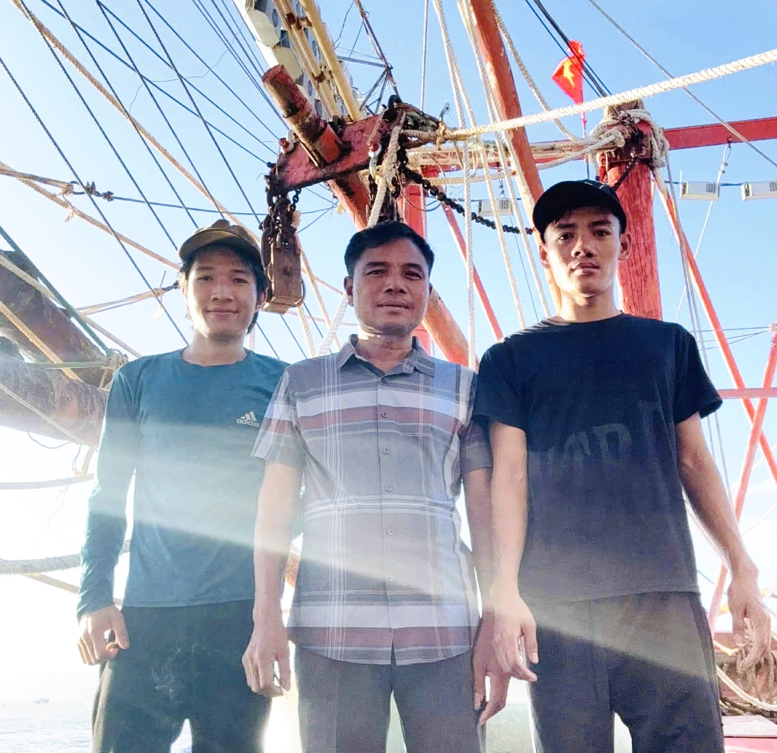 លោក Ho Dang Vo (កណ្ដាល) និងកូនប្រុសពីរនាក់នៅលើទូកនេសាទ QB92981TS - រូបភាព៖ T.L