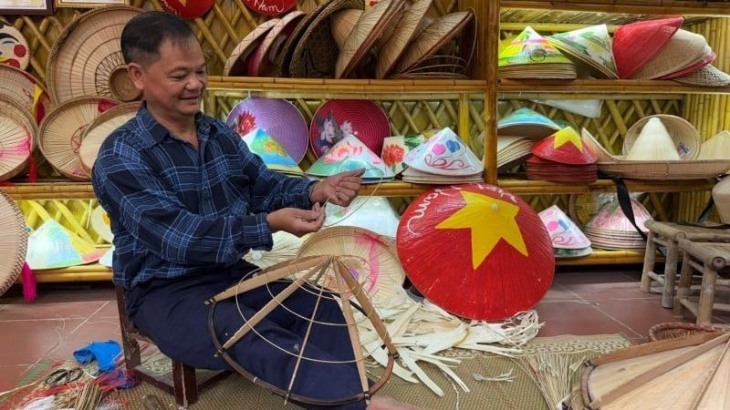 El artesano Le Van Tuy deshilacha meticulosamente el aro del sombrero cónico.