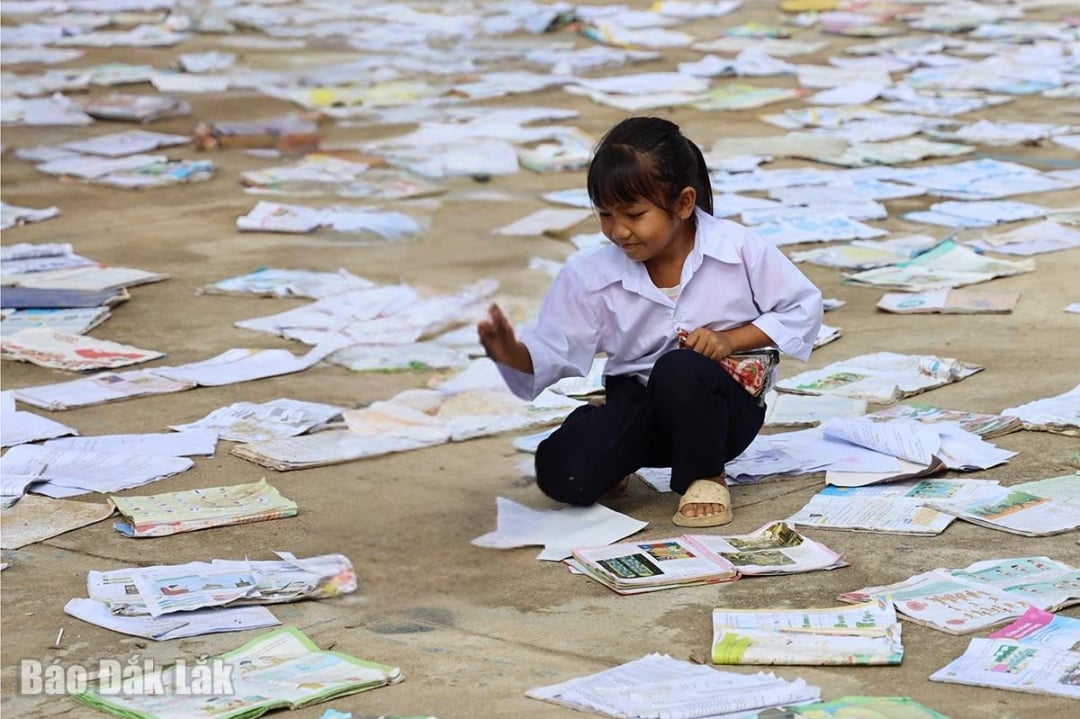 Um aluno da Escola Primária Phu Mo secando livros encharcados de lama.