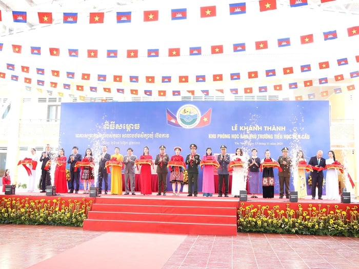 Bộ trưởng Bộ Quốc phòng hai nước và các đại biểu cắt băng khánh thành khu phòng học bán trú Trường Tiểu học Bến Cầu. Ảnh: Hồ Lam