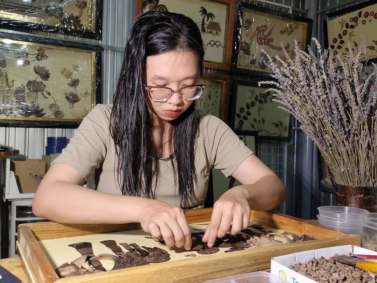Nguyễn Băng Nhi lắp ráp tranh từ các chi tiết làm bằng gáo dừa. Ảnh: Minh Đảm.