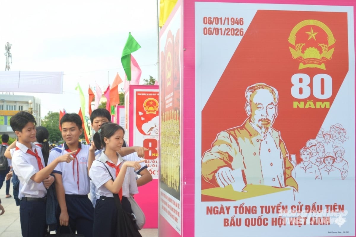 Các em học sinh phường Rạch Giá xem tranh cổ động tấm lớn tuyên truyền kỷ niệm 80 năm Ngày Tổng tuyển cử đầu tiên bầu Quốc hội Việt Nam được trưng bày tại Công viên Nguyễn Trung Trực. Ảnh: Trung Chánh.