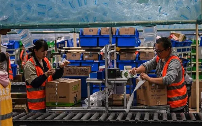 Nhân viên đóng gói hàng hóa tại một chi nhánh kho vận của Alibaba ở Vô Tích, tỉnh Giang Tô, Trung Quốc. (Ảnh: AFP/TTXVN)