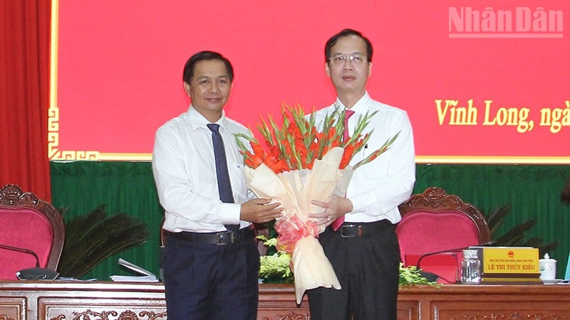 O secretário do Comitê Provincial do Partido de Vinh Long, Tran Van Lau, entregou flores para parabenizar o novo presidente do Comitê Popular Provincial de Vinh Long, Tran Tri Quang.
