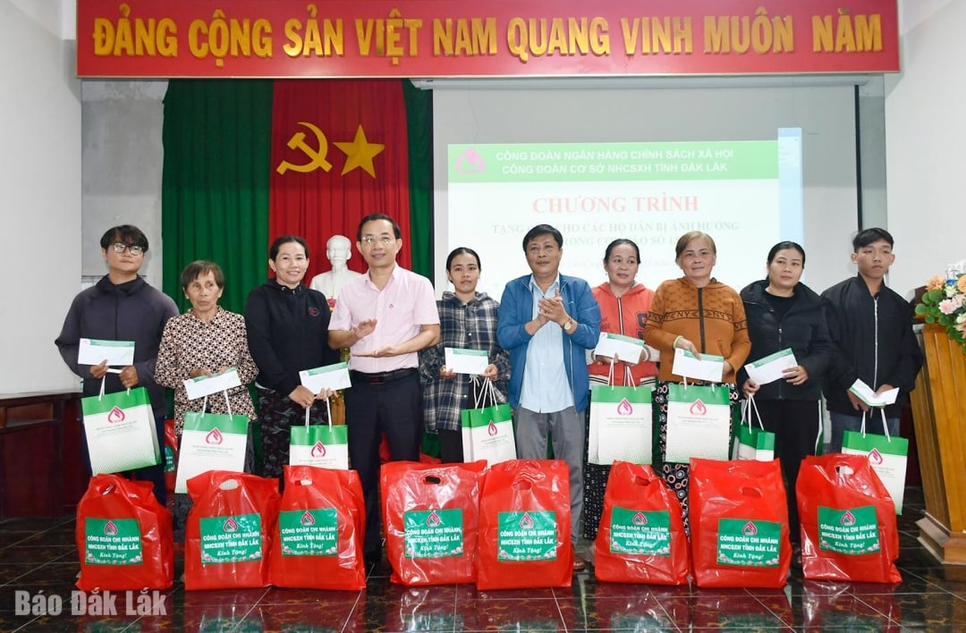 Lãnh đạo Chi nhánh NHCSXH tỉnh Đắk Lắk và lãnh đạo xã Xuân Cảnh trao quà cho người dân.