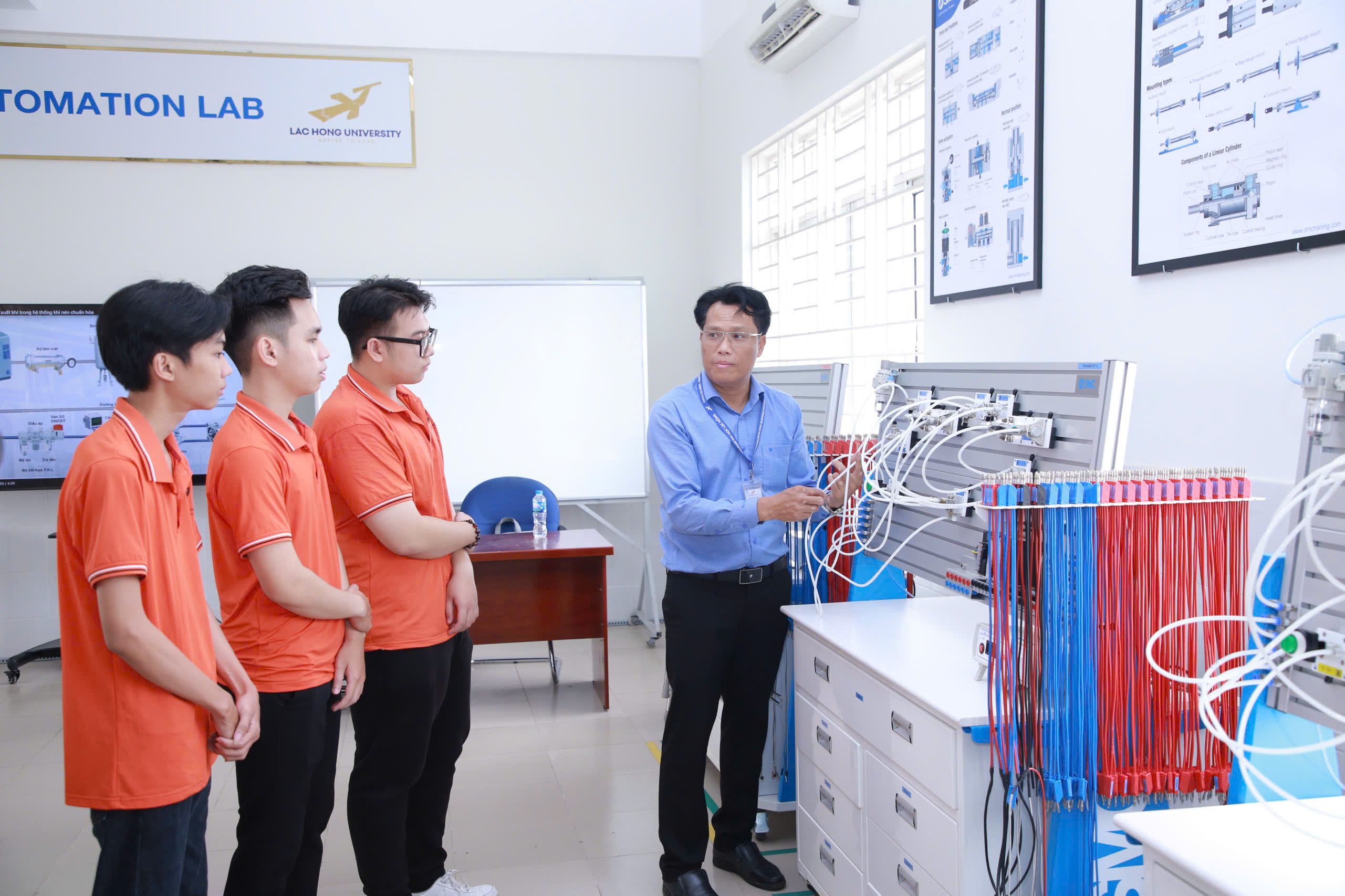 Tiến sĩ Phạm Văn Toản, Trưởng khoa Cơ điện - Điện tử Trường đại học Lạc Hồng hướng dẫn sinh viên làm quen với thiết bị khí nén công nghệ tự động hóa. Ảnh: Công Nghĩa