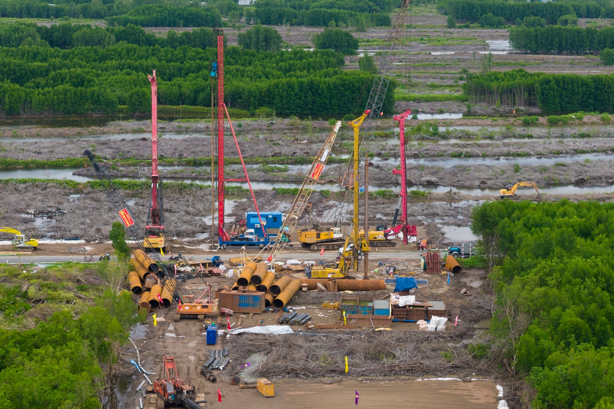 技術者と監理コンサルタントが、橋本体建設の基礎工事の一つである杭打ち工事に備えてケーシングパイプを立てる作業を行っています。 Lực lượng kỹ sư, tư vấn giám sát đang triển khai công tác dựng ống vách chuẩn bị cho thi công cọc khoan nhồi, một trong những hạng mục nền tảng để xây dựng thân cầu.