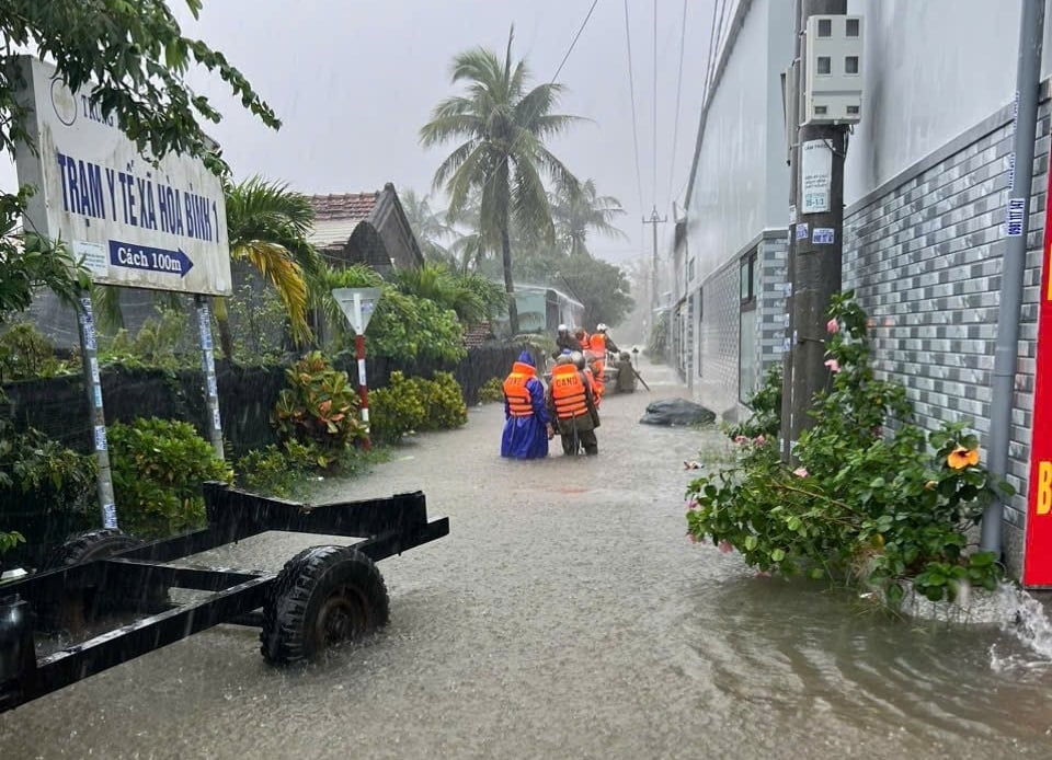 Lực lượng chức năng hỗ trợ người dân di dời. Ảnh: A Toàn.